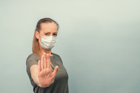 A girl is putting on a protective mask. Respiratory protection from coronavirus. Keep the distance. Personal protective equipment for a pandemic of a viral infection. Covid-19.の写真素材