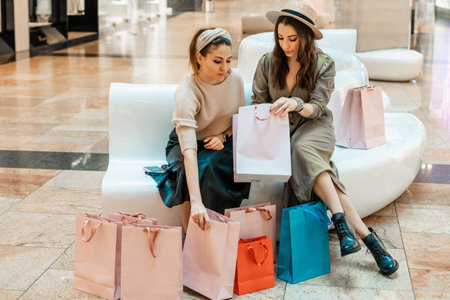 Girls are resting on the couch in the mall. Shopping, entertainment and leisure. Break in purchases.の写真素材