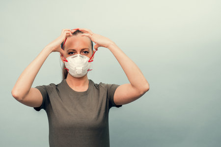 A girl is putting on a protective mask. Respiratory protection from coronavirus. Personal protective equipment for a pandemic of a viral infection. Covid-19.の写真素材
