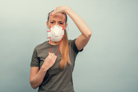 A girl is putting on a protective mask. Respiratory protection from coronavirus. Personal protective equipment for a pandemic of a viral infection. Covid-19.の写真素材
