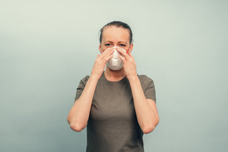 A girl is putting on a protective mask. Respiratory protection from coronavirus. Personal protective equipment for a pandemic of a viral infection. Covid-19.の写真素材
