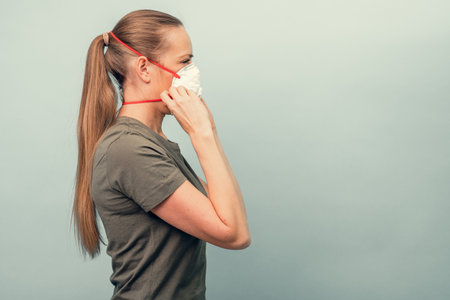 A girl is putting on a protective mask. Respiratory protection from coronavirus. Personal protective equipment for a pandemic of a viral infection. Covid-19.の写真素材