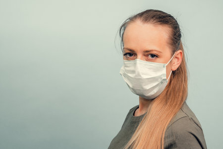 A girl is putting on a protective mask. Respiratory protection from coronavirus. Personal protective equipment for a pandemic of a viral infection. Covid-19.の写真素材