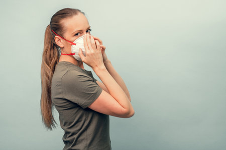 A girl is putting on a protective mask. Respiratory protection from coronavirus. Personal protective equipment for a pandemic of a viral infection. Covid-19.の写真素材
