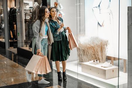 Trade, buyers. Two beautiful girls make purchases in a shopping center, go shopping. The joy of consumption.の写真素材