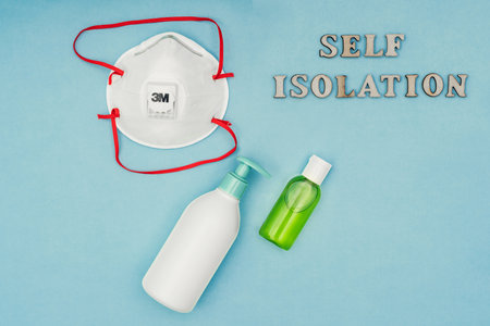 Russia, Moscow - March 21, 2020: Coronavirus, Covid-19. Inscription self-isolation, a protective mask, an antiseptic and a dispenser for living soap on a blue background. 3 M maskの写真素材
