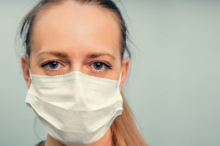 A girl is putting on a protective mask. Respiratory protection from coronavirus. Personal protective equipment for a pandemic of a viral infection. Covid-19.の写真素材