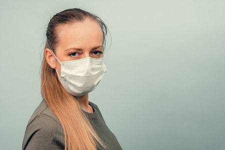A girl is putting on a protective mask. Respiratory protection from coronavirus. Personal protective equipment for a pandemic of a viral infection. Covid-19.の写真素材