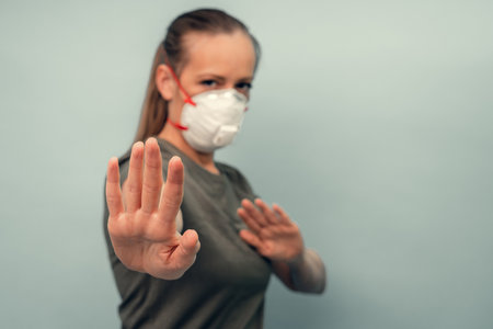A girl is putting on a protective mask. Respiratory protection from coronavirus. Keep the distance. Personal protective equipment for a pandemic of a viral infection. Covid-19.の写真素材