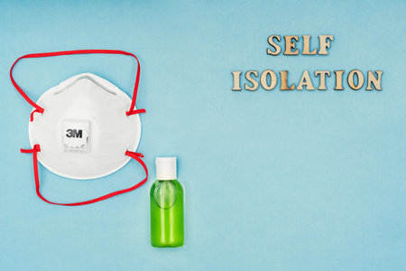 Russia, Moscow - March 21, 2020: Coronavirus, Covid-19. Inscription self-isolation, a protective mask, an antiseptic and a dispenser for living soap on a blue background. 3 M maskの写真素材