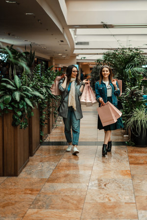 Trade, buyers. Two beautiful girls make purchases in a shopping center, go shopping. Green hothouse in a shopping center. The joy of consumption.の写真素材