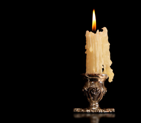 burning old candle vintage bronze candlestick. Isolated On Black Background.の写真素材