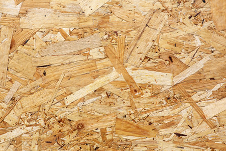 OSB boards are made of brown wood chips sanded into wooden background. Top view of OSB wood veneer background, tight, seamless surfaces.