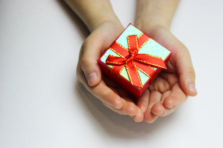 a gift in childrens hands, on a white background, a girl gives giftsの写真素材