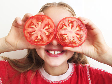 A girl holding red ripe tomatoes in her hands, a girl is happy, a girl on a white backgroundの写真素材