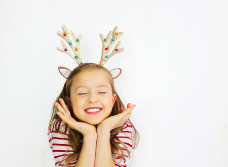 beautiful girl Santa deer, in a red sweater for Christmas and New Years gift. Have a happy little girl on a white background banner. Girl rejoices and waits for giftsの写真素材