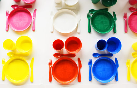 Empty white plastic plate, cup, fork and spoon over white background with copy space. Dining set of...