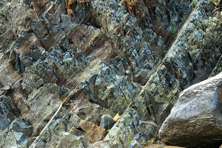 A fragment of a blue-gray stone rock close-up, the stone breed has sharp ledges, a large stone on...
