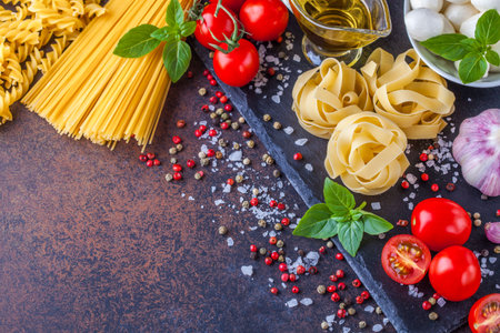 Ingredients for pasta with mozzarella and tomatoes on a dark background, horizontally with a notepad for writingの写真素材