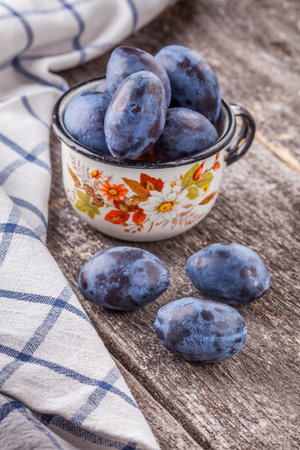 plum in a cup on a wooden boardの写真素材