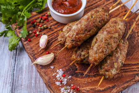 Lulya-kebab. Shish kebab on a stick, minced meat. Traditional Caucasian dish. On a cutting board, with green salad, ketchup, spices.の写真素材