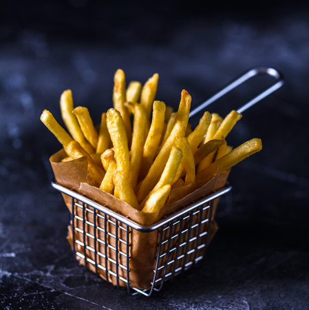 French fries in a basket on a black background, copyspace, square