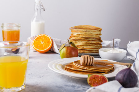 Pancakes with honey, fruit and coffee on a gray background, horizontally, figs, alginate juice, raspberry jam, sour cream, flat lay, copyspaceの写真素材