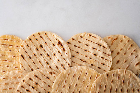 Stack of homemade whole wheat flour tortilla, on white background.