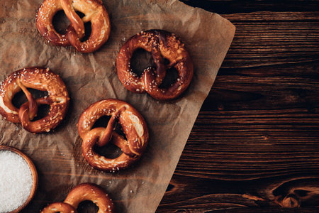 Traditional German Savory Lye Pretzel with Salt on Piece of Parchment Paper. Poster Banner for Bakery. Copy Space.Top View.Toned image.の写真素材