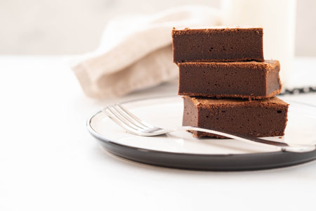 Chocolate brownie square pieces in stack on white plate. American traditional delicious dessert. Copy space.の写真素材
