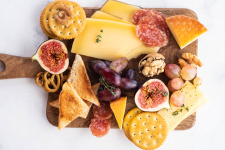 Cheese plate served with grapes, jam, figs, crackers and nuts on a white background. Copy space. Top view.の写真素材