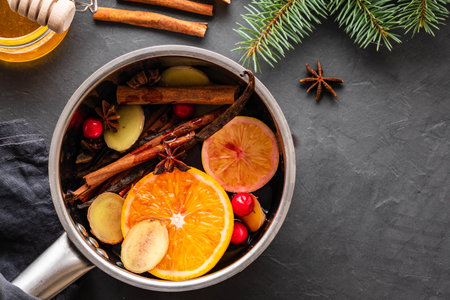 Mulled wine hot drink with citrus, apple and spices in aluminum casserole and Fir branch on background.の写真素材