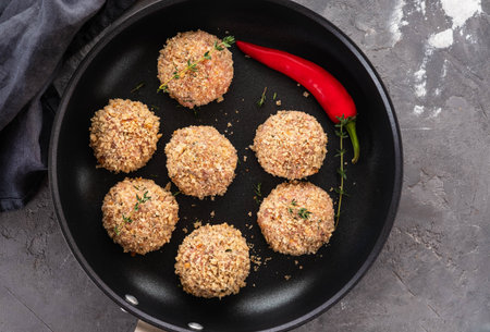 Raw meatballs in a pan on black background. Copy space.