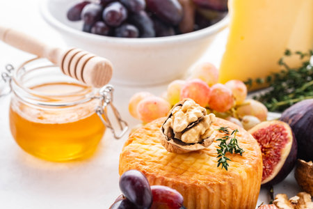 Cheese plate served with grapes, jam, figs, crackers and nuts on a background.の写真素材