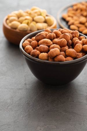 Assorted nuts in bowls on a black background. Copy space.の写真素材