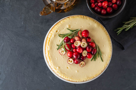 Classic cheesecake with cranberries and rosemary on a dark background. Winter version of cheesecake. Christmas cheesecake.の写真素材