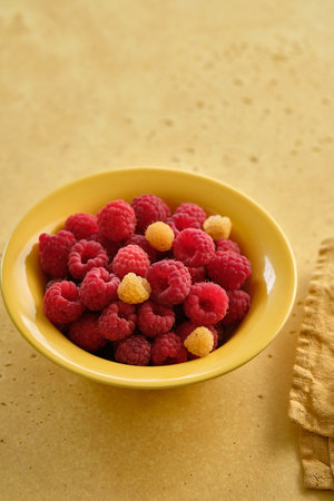 Raspberries in a yellow plate. Copy space.
