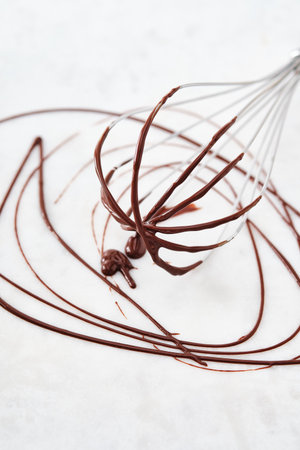 Liquid chocolate dripping off a whisk, isolated on white backgroundの写真素材