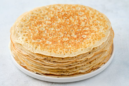 Crepes, thin pancakes with honey and butter on a white plate. Close up.