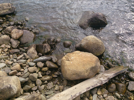 Board and stones lie on the bank of the riverの写真素材