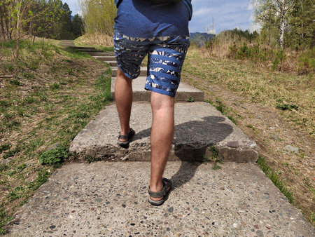 a man in blue shorts steps up the stairs which leads to the forestの写真素材
