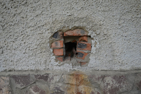 a hole in a concrete wall, brick wall sand smal brown pipe, oldの写真素材