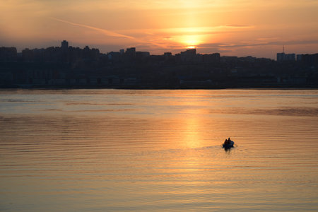 a couple of lovers ride a boat at a beautiful sunset against the background of the cityの写真素材