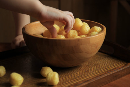 Baby hand takes from bamboo bowl corn ball.