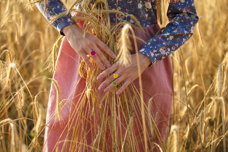 woman with colored rings holding wheat spikesの写真素材