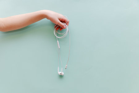 children's hand keeps the headphones on a blue background.musicの写真素材