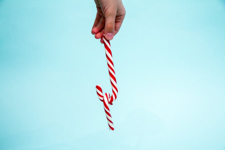 hand holding a lollipop on a blue background.の写真素材