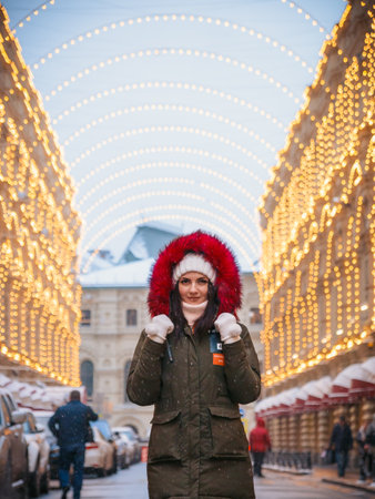 Winter portrait of a young woman against the backdrop of decorated buildings.の写真素材