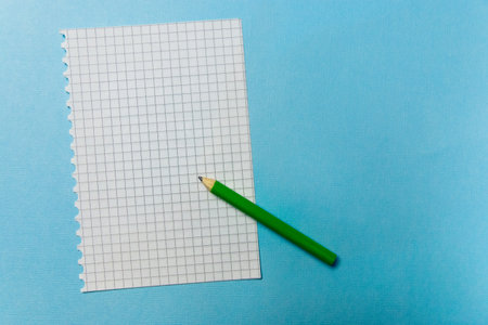 notebook and a green pencil on blue background. Office theme.
