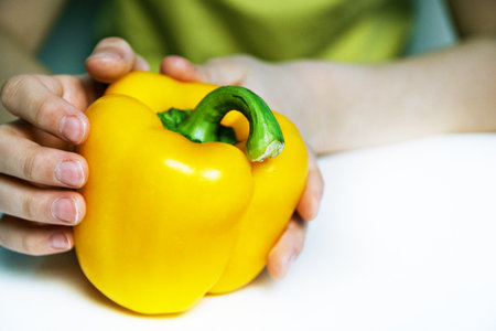 yellow bell peppers in children's hands.の写真素材